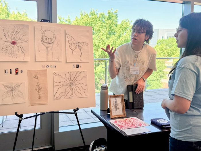 A person talks about a poster display while another person listens.