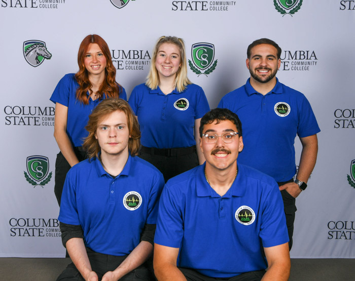 A group of people pose in front of a white background.